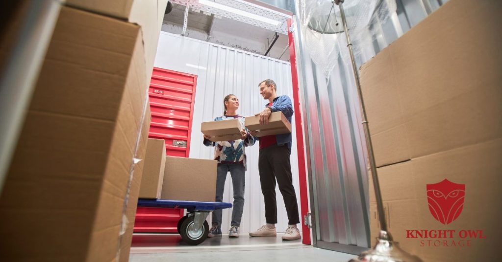 A man and woman holding packing boxes inside a clean, secure indoor storage unit.
